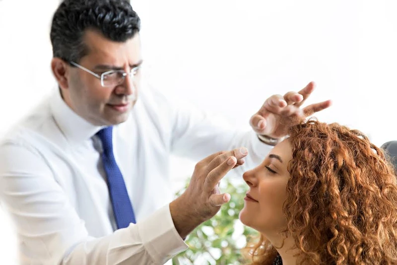 Dr. Cenk Teker examining a patient's nose profile at the clinic