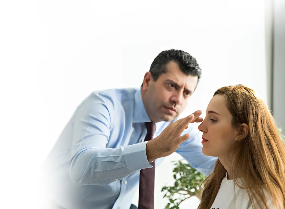 Op. Dr. Cenk Teker examining a patient's nose during a consultation